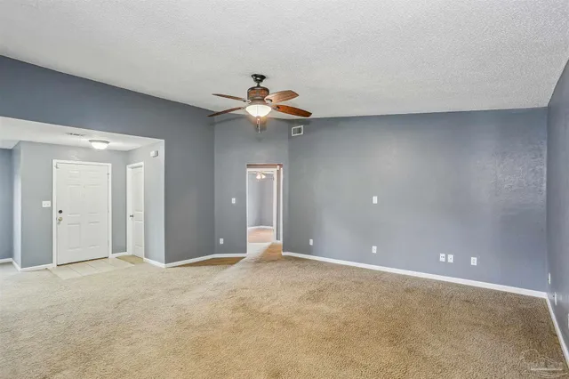 a view of an empty room with chandelier fan