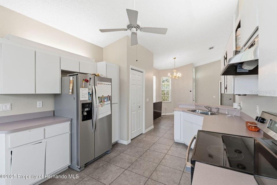 10290 Adler Street Spring Hill, FL 34608 - Photo 21 of 34 a kitchen with stainless steel appliances a refrigerator a sink dishwasher a oven with white cabinets and wooden floor
