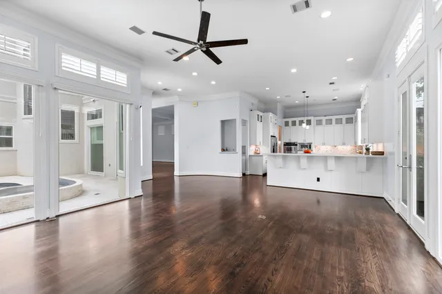 a view of an empty room and kitchen with wooden floor