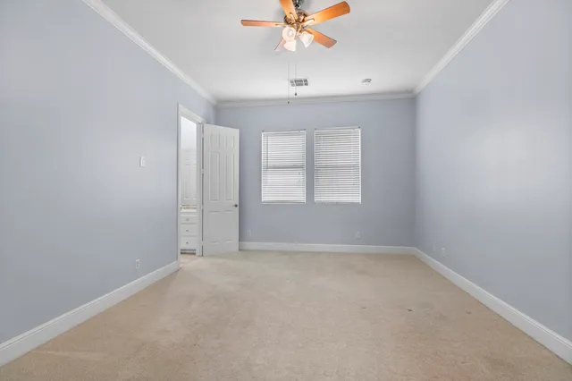 an empty room with a chandelier fan and windows