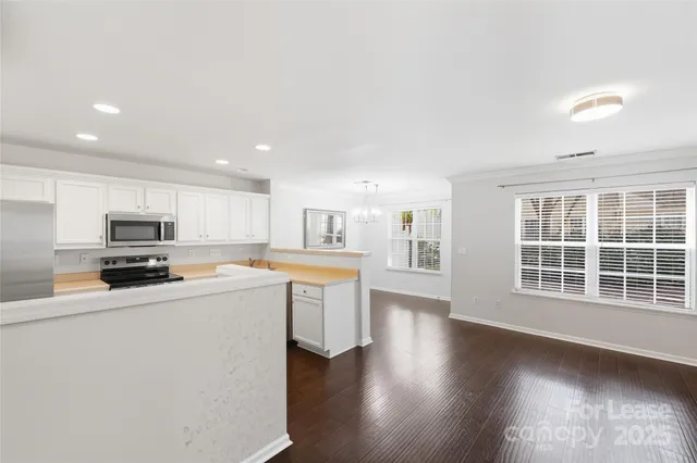 a kitchen with stainless steel appliances a sink a stove a microwave a center island and windows