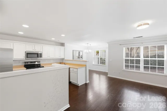 a kitchen with stainless steel appliances a sink a stove a microwave a center island and windows