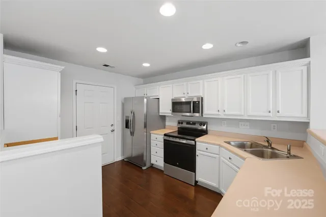 a kitchen with stainless steel appliances a refrigerator stove and white cabinets