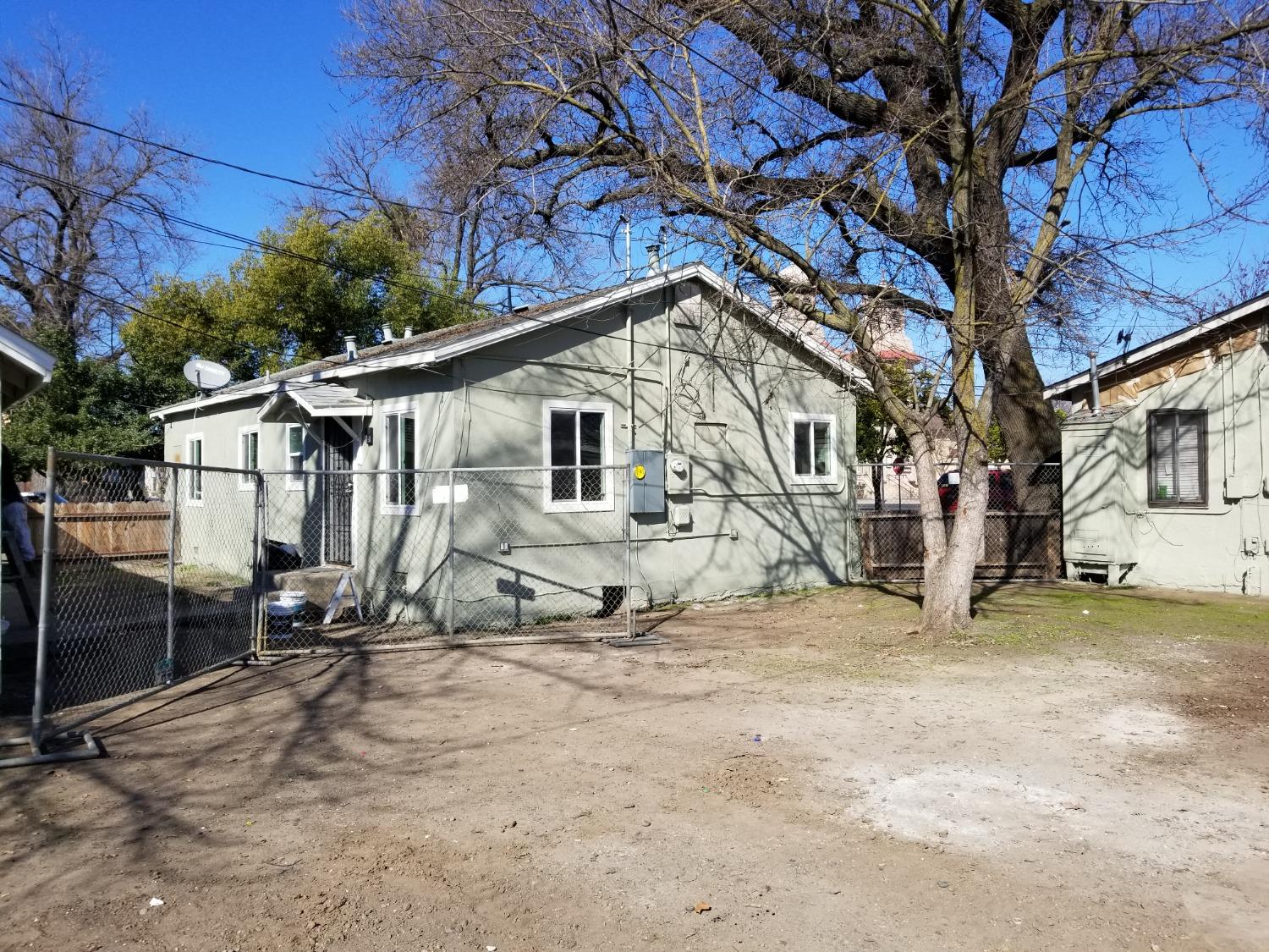618 J Street Modesto, CA 95354 - Photo 11 of 38 a view of a white house with a large tree and wooden fence