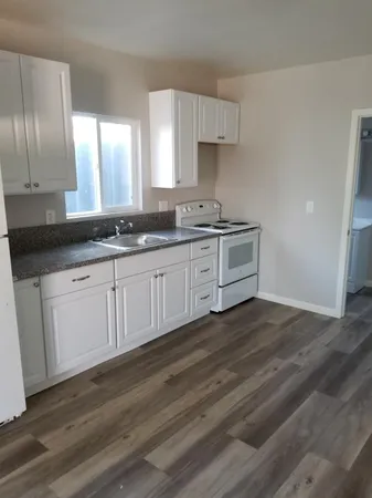 a kitchen with granite countertop white cabinets and a sink