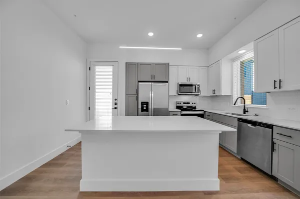 a kitchen with a refrigerator a sink and dishwasher with wooden floor