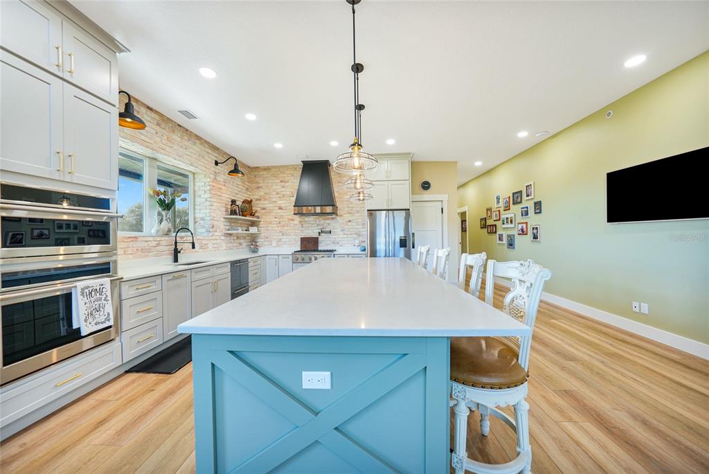 3321 Southwest Martin Lane Arcadia, FL 34266 - Photo 15 of 81 a kitchen with stainless steel appliances kitchen island granite countertop a sink a microwave a stove and white cabinets with wooden floor