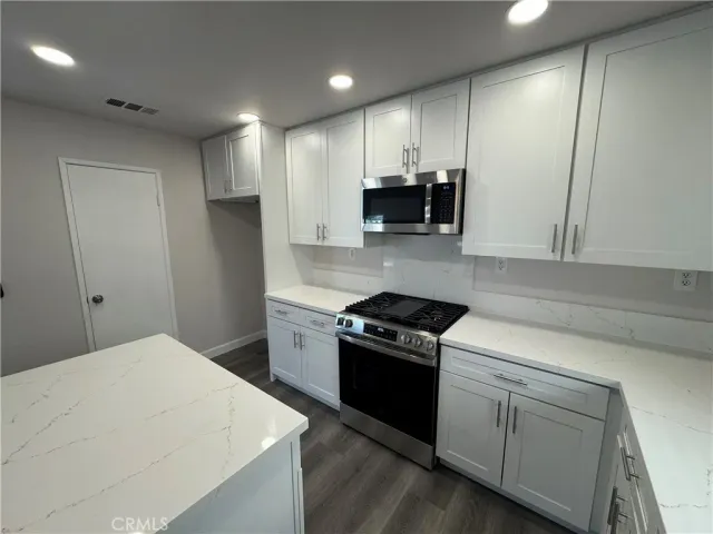 a kitchen with stainless steel appliances a stove a sink a refrigerator and a microwave