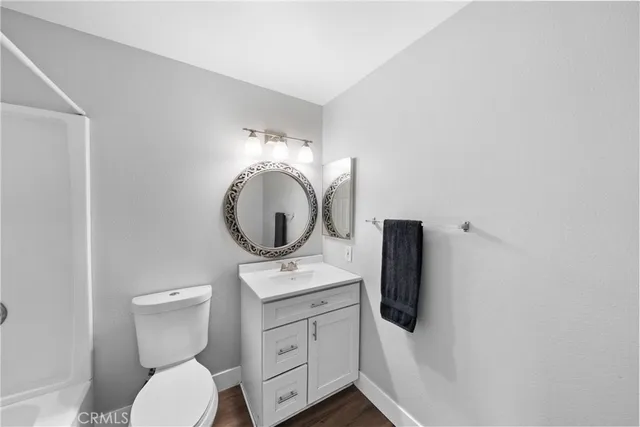 a bathroom with a toilet sink vanity granite and mirror