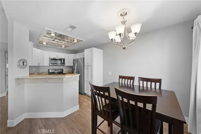 a view of a dining room with furniture a chandelier and wooden floor