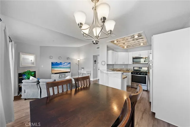 a view of a dining room and livingroom with furniture wooden floor a chandelier