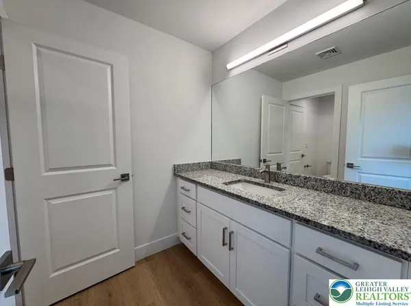 a bathroom with a granite countertop double vanity sink and two mirror
