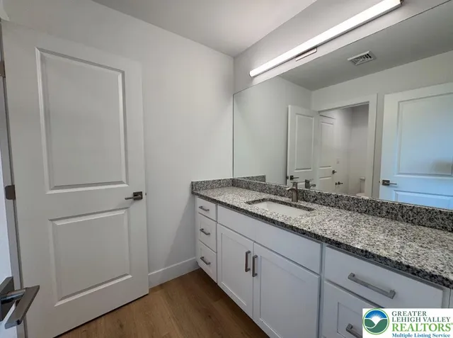 a bathroom with a granite countertop double vanity sink and two mirror