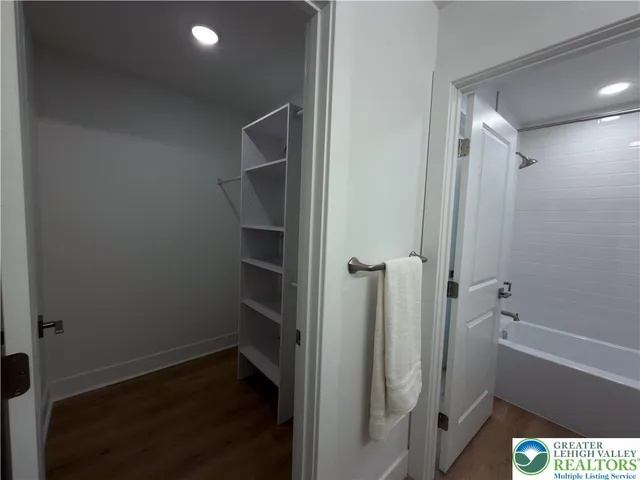 a view of room with walk in closet and wooden floor