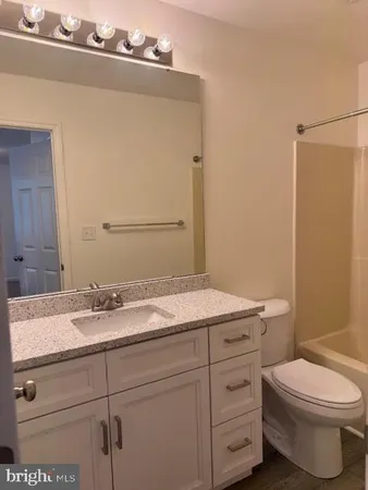 a bathroom with a granite countertop toilet sink and mirror