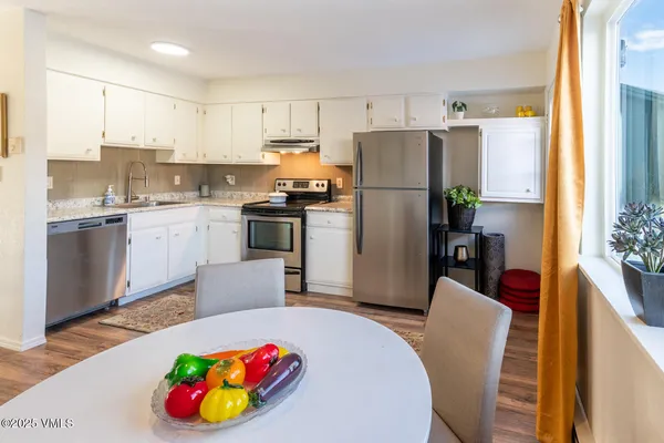 a kitchen with a refrigerator a stove a sink dishwasher with a dining table and chairs