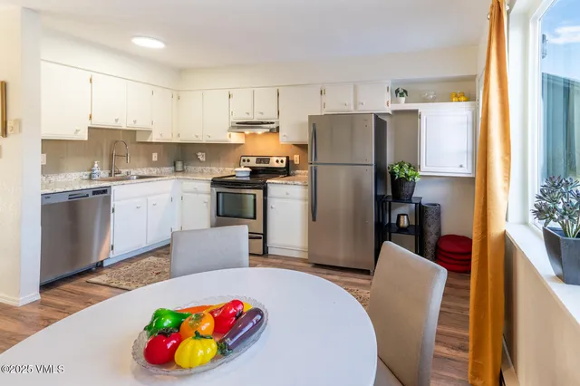 a kitchen with a refrigerator a stove a sink dishwasher with a dining table and chairs