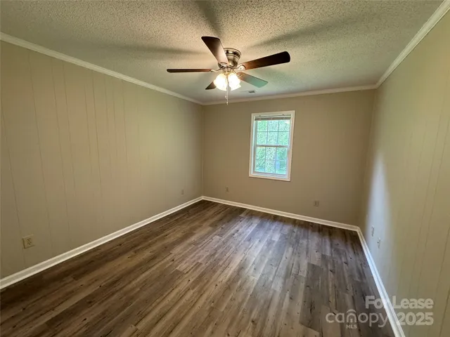 an empty room with wooden floor ceiling fan and windows
