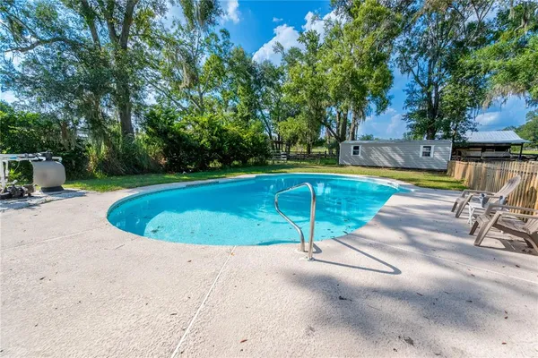 a view of a swimming pool with a patio and a yard