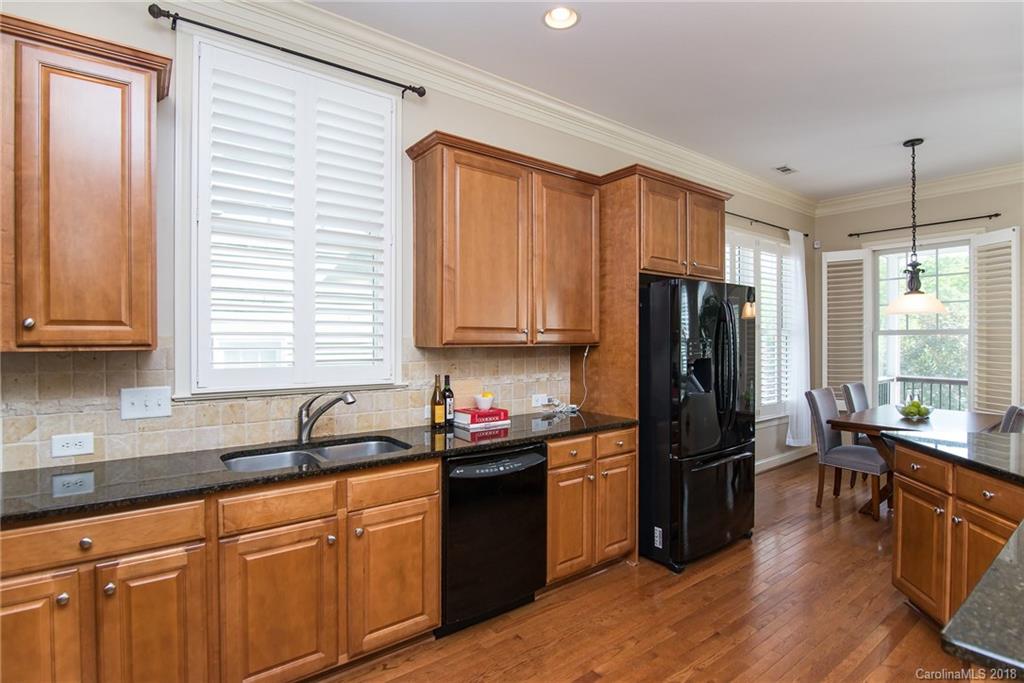 944 Gardenia Street Fort Mill, SC 29708 - Photo 19 of 35 a kitchen with granite countertop a refrigerator a sink dishwasher a stove and white cabinets with wooden floor