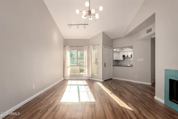a view of an empty room with wooden floor fireplace and a window