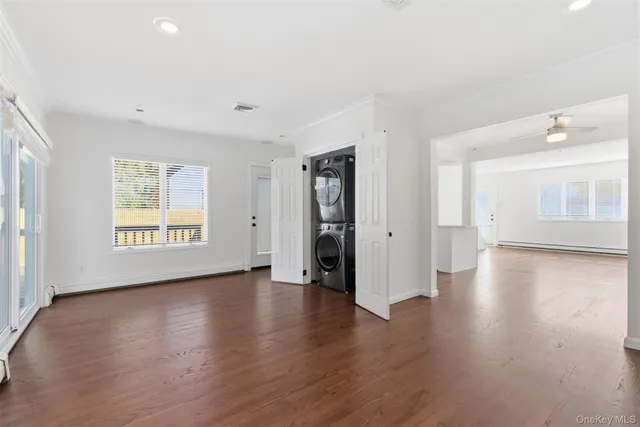 a view of an empty room with wooden floor and windows