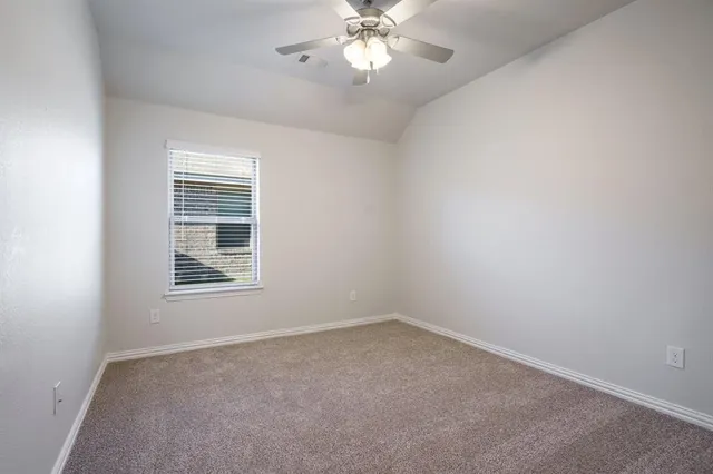 an empty room with a chandelier fan and windows