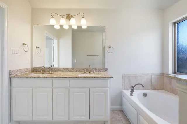 a bathroom with a granite countertop sink a large mirror and a bathtub
