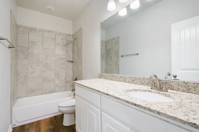 a bathroom with a granite countertop sink toilet mirror and bathtub