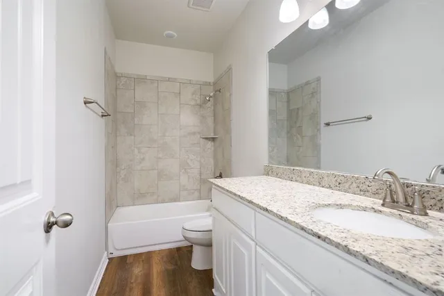 a bathroom with a granite countertop sink a toilet and shower