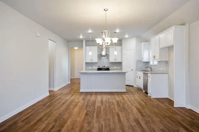 a large kitchen with granite countertop a large counter top a sink stainless steel appliances and cabinets