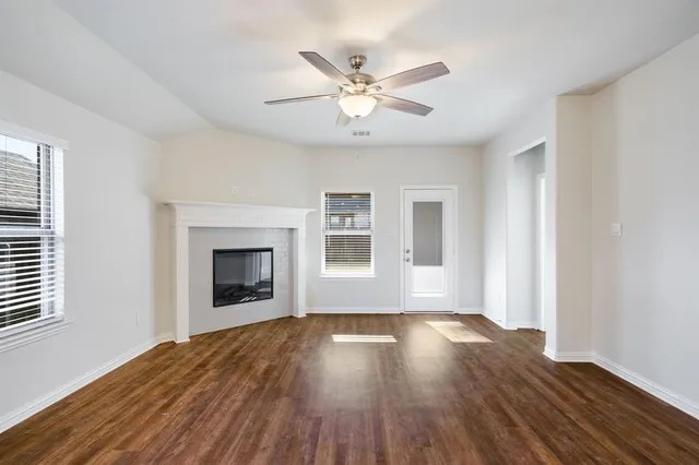 an empty room with wooden floor windows and fireplace