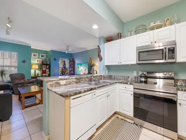 a kitchen with stainless steel appliances granite countertop a stove top oven a sink dishwasher and white cabinets