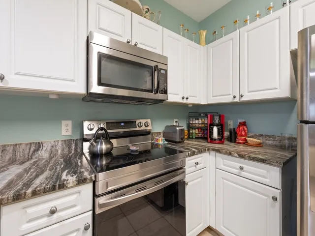 a kitchen with stainless steel appliances granite countertop a sink dishwasher a stove and a microwave oven with cabinets