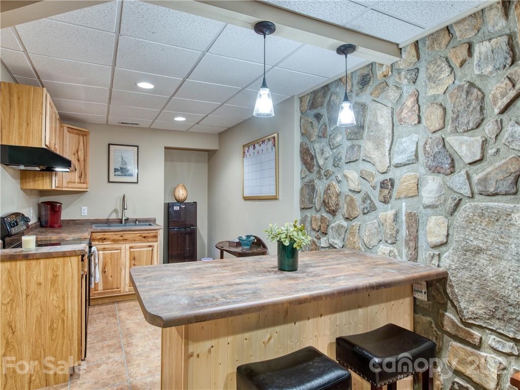 1052 Springbrook Farm Road Waynesville, NC 28786 - Photo 24 of 37 a kitchen with stainless steel appliances granite countertop a sink a stove a dining table and chairs with wooden floor