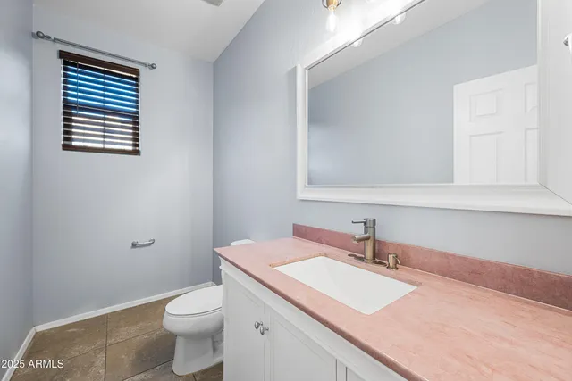 a bathroom with a granite countertop sink and a toilet