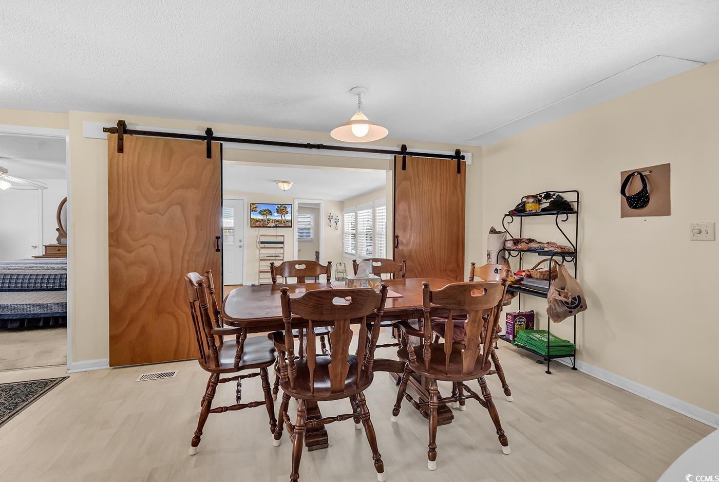 449 Rainbow Drive Murrells Inlet, SC 29576 - Photo 12 of 33 Dining space featuring a barn door, light wood finished floors, a textured ceiling, and ceiling fan