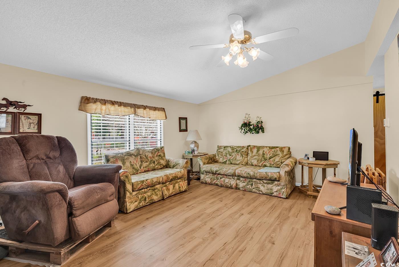 449 Rainbow Drive Murrells Inlet, SC 29576 - Photo 2 of 33 Living room featuring lofted ceiling, light wood-style flooring, a ceiling fan, a barn door, and a textured ceiling