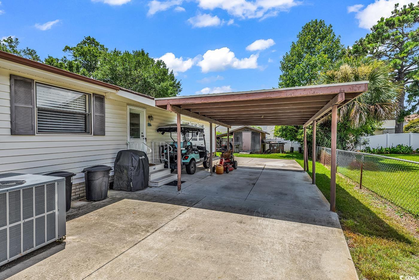 449 Rainbow Drive Murrells Inlet, SC 29576 - Photo 26 of 33 View of patio / terrace featuring a storage unit, concrete driveway, area for grilling, and a carport