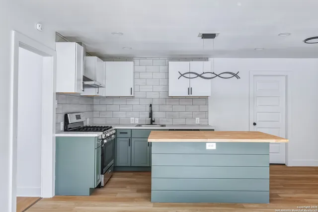 a kitchen with a stove cabinets and wooden floor