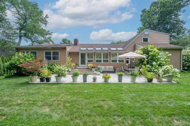 a view of house with a big yard and potted plants