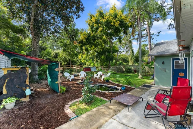 a view of a patio with table and chairs potted plants and a large tree