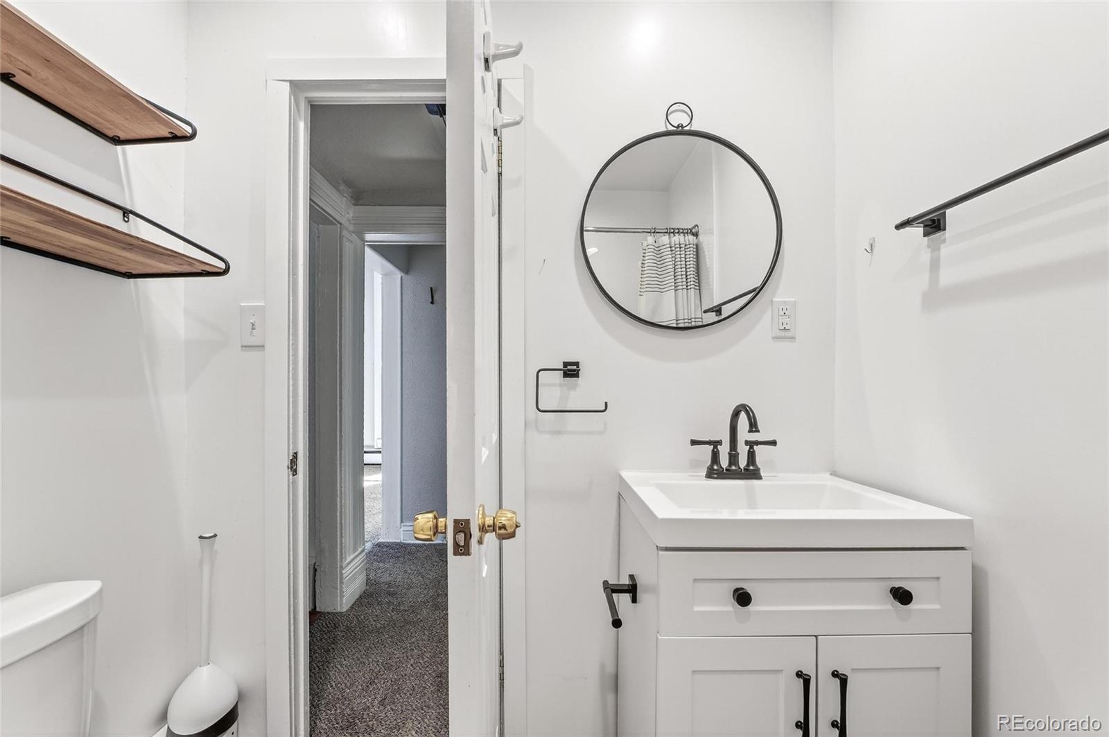 3127 West 28th Avenue, Unit 2 Denver, CO 80211 - Photo 8 of 30 a bathroom with a sink a toilet and a mirror