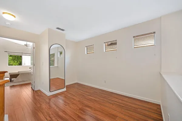 an empty room with wooden floor and windows