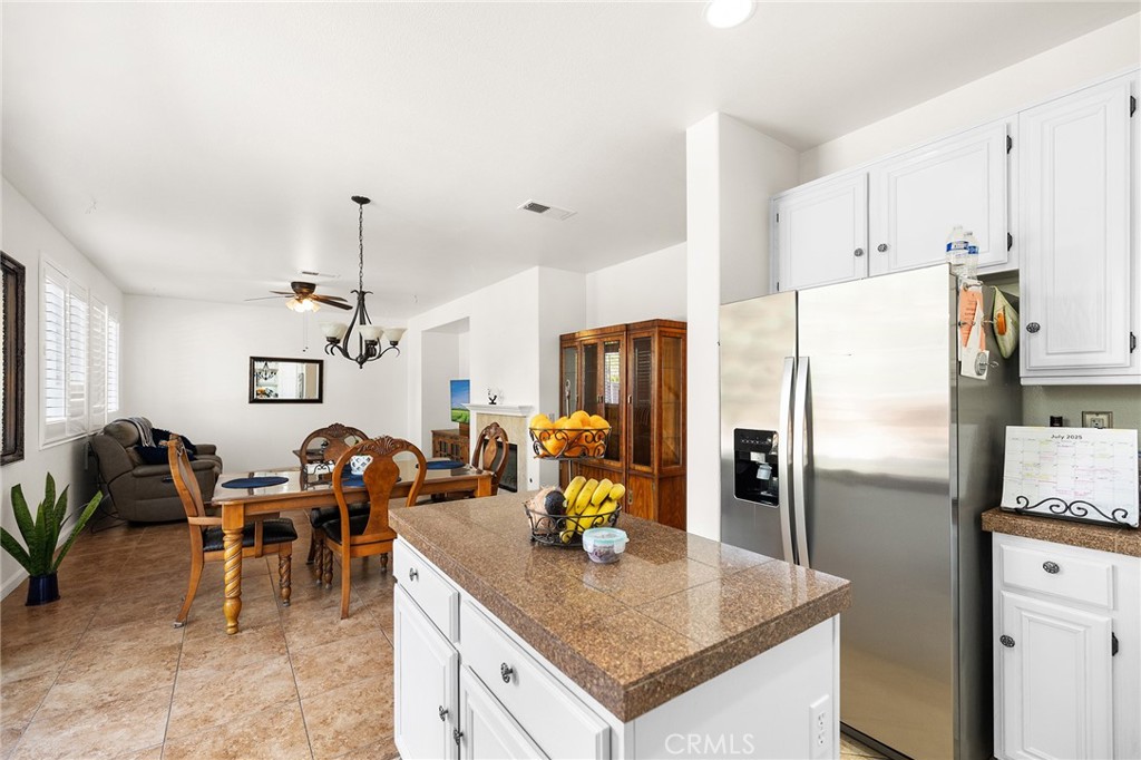 1427 Marble Canyon Way Chula Vista, CA 91915 - Photo 16 of 60 a kitchen with stainless steel appliances granite countertop a table chairs and a refrigerator
