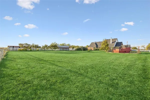 a view of a house with a big yard and large trees