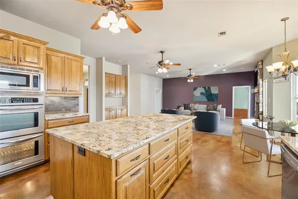 a large kitchen with kitchen island a stove a sink dishwasher and white cabinets with wooden floor