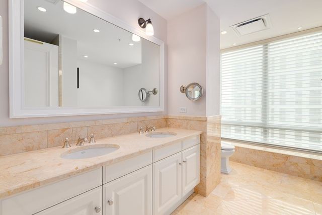 a bathroom with a granite countertop sink mirror and a bathtub