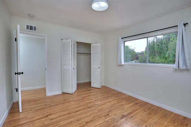 a view of empty room with wooden floor and fan