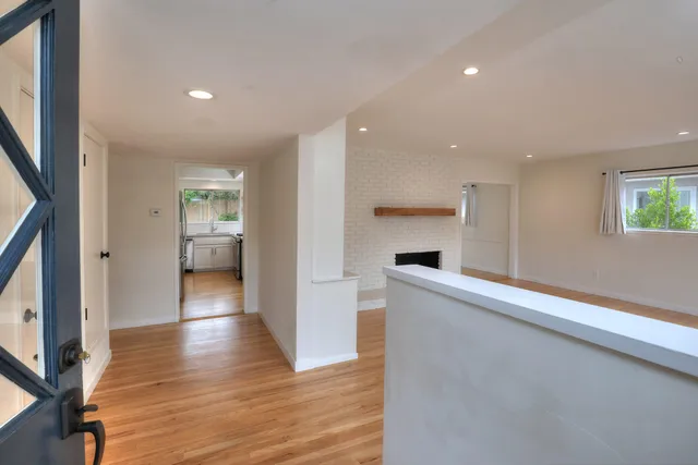 an empty room with windows fireplace and wooden floor